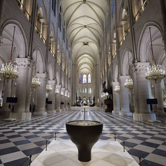 Nave restaurada de Notre Dame de Paris, con sus bóvedas góticas, arañas y la nueva pila bautismal