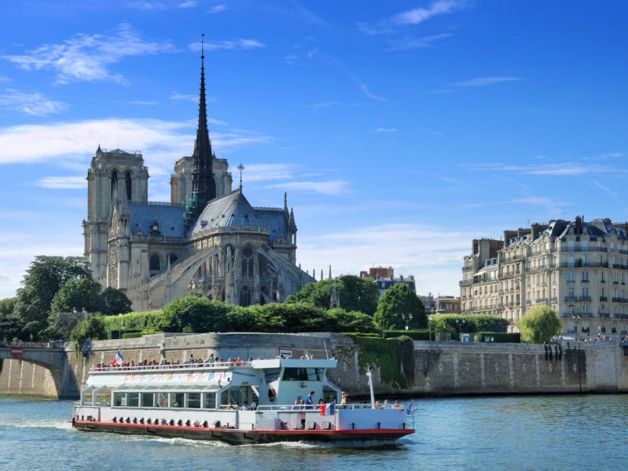 Barco turístico navegando por el Sena frente a la cabecera de Notre Dame de Paris