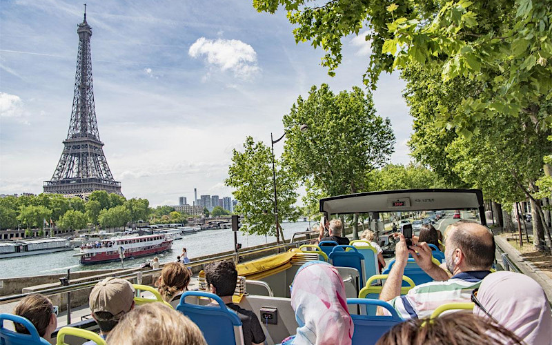 Grupo de turistas en el piso superior de un autob?s panor?mico de dos pisos con vistas a la Torre Eiffel y el Sena